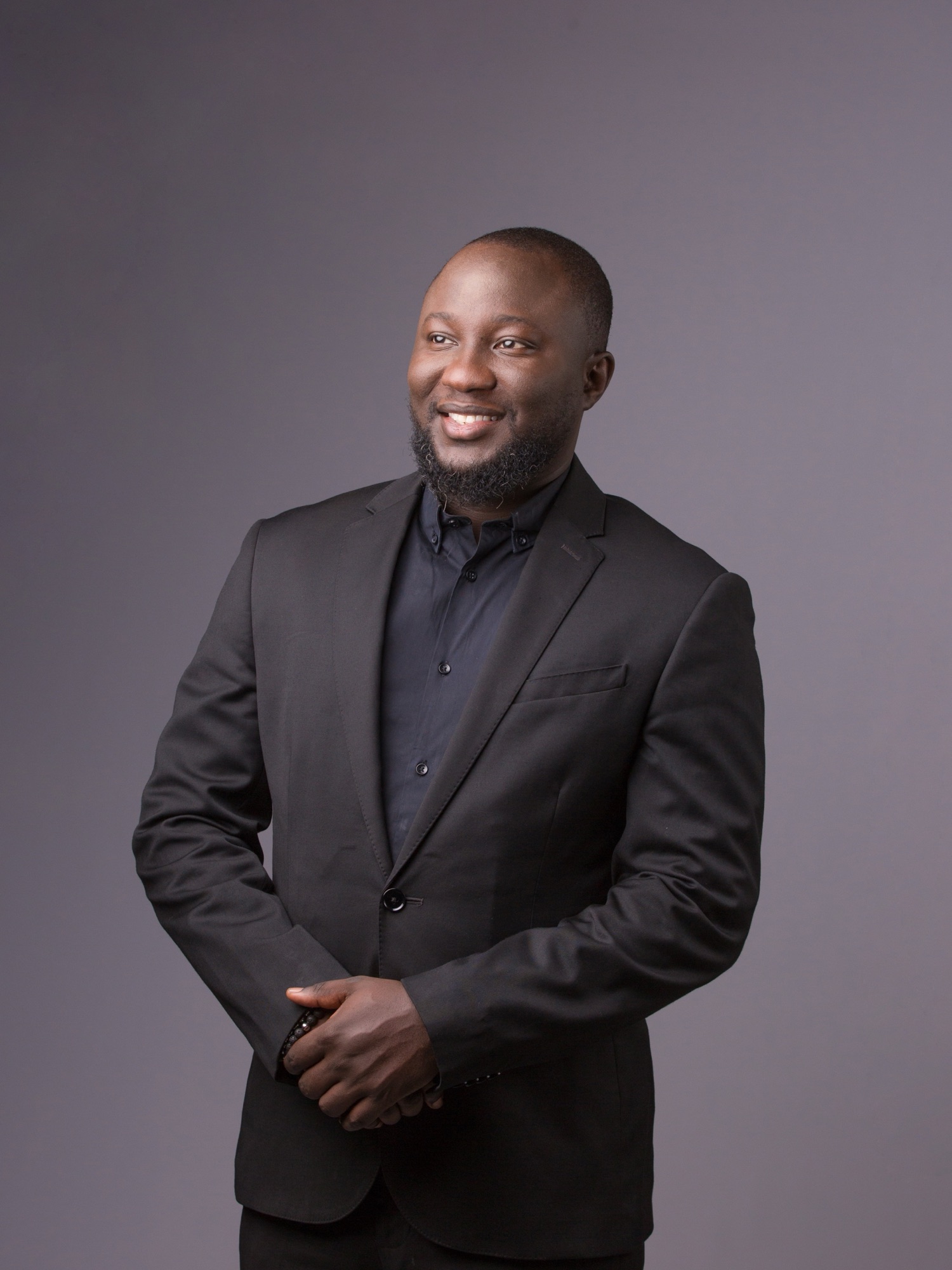 Oluwaseun Dania in a charcoal suit, laughing