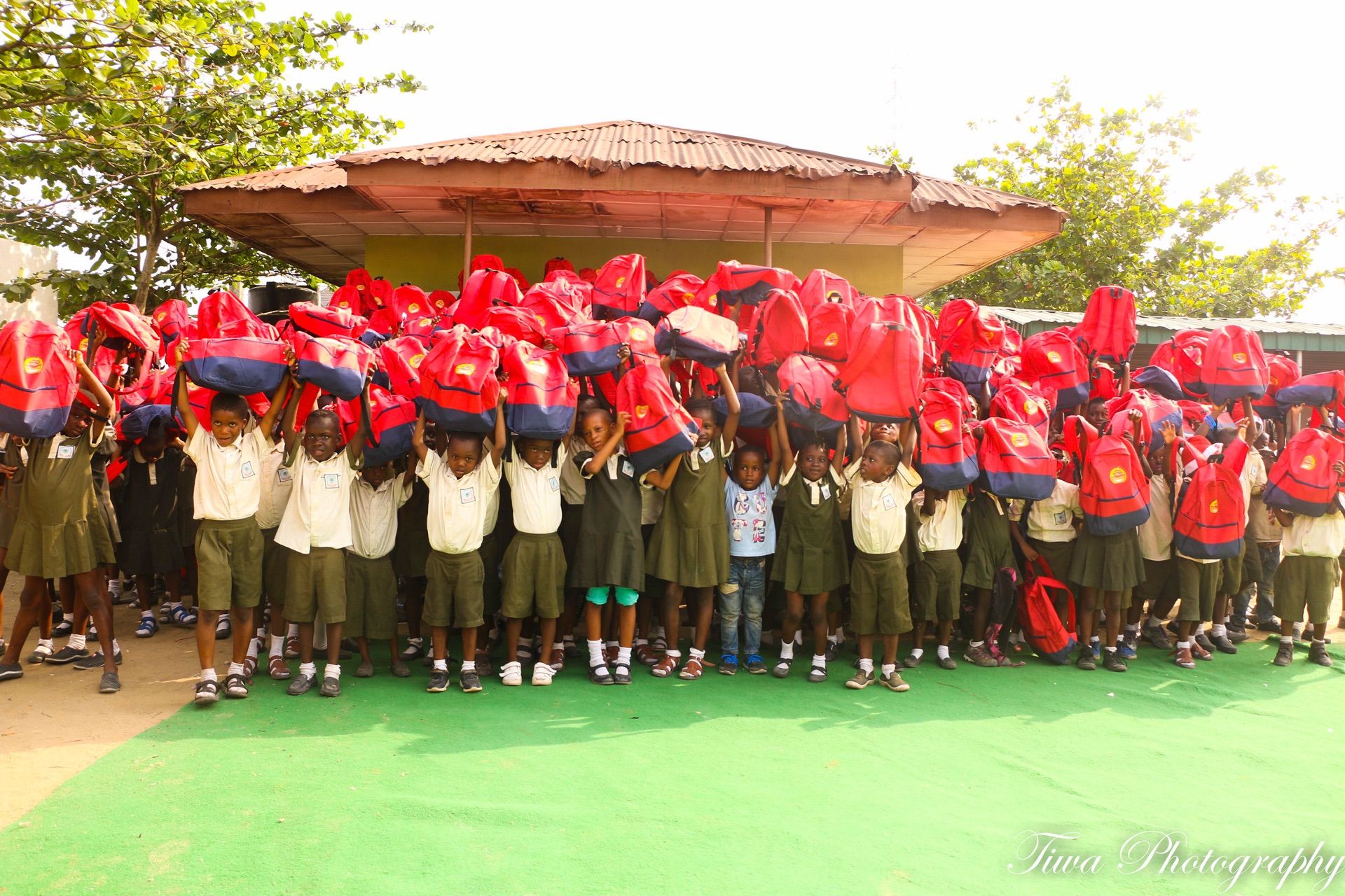Children raising their new backpacks overhead at a Foundation programme
